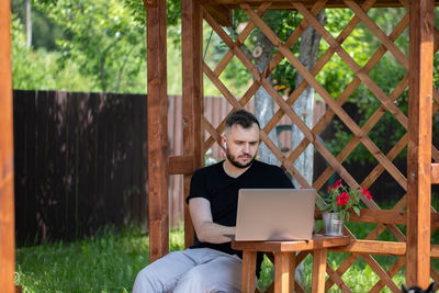 Young man using mobile phone while sitting outdoors