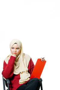 Young woman sitting on seat against white background