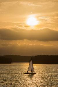 Sailboat sailing on sea against sky during sunset