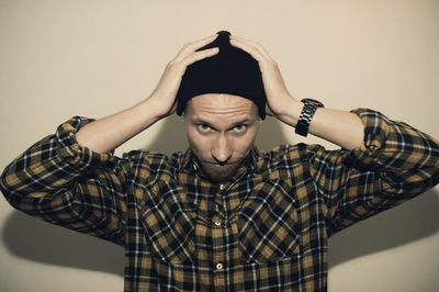 Portrait of young man standing against wall