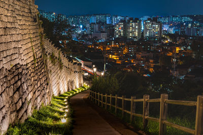 Illuminated street amidst buildings in city at night