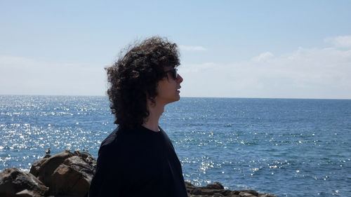 Young woman looking at sea against sky