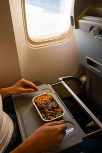 Midsection of woman holding airplane at window