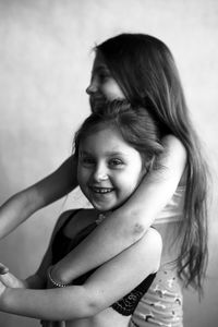 Portrait of smiling girl with sister against wall
