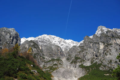 Low angle view of rocky mountains against clear blue sky