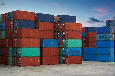 Cargo containers against sky during sunset