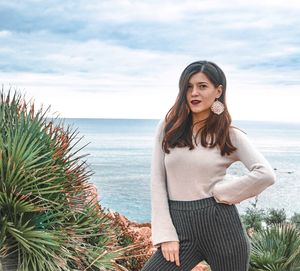 Young woman standing at beach against sky