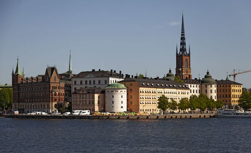 Buildings by sea against clear sky