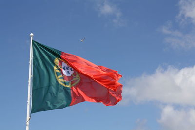 Low angle view of red flag against blue sky