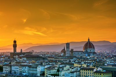 Buildings in city against sky during sunset