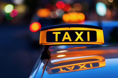 Close-up of illuminated taxi sign in city at night