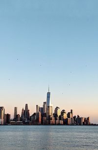 Sea by modern buildings in city against sky