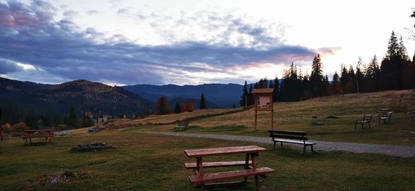 Empty bench on field against sky