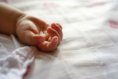 Close-up of baby hand on bed at home