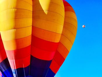 Low angle view of hot air balloons flying against clear blue sky