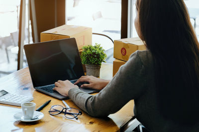 Midsection of woman using laptop on table