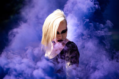 Young woman with make-up standing against smoke