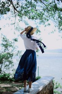 Rear view of woman standing against sea