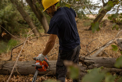 Man cutting wood with chain saw in forest