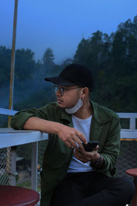 Side view of young man using mobile phone while sitting at outdoor cafe