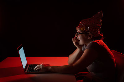 Low angle view of woman using mobile phone while sitting against black background