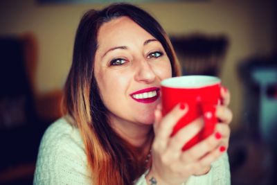 Close-up of smiling young woman drinking coffee