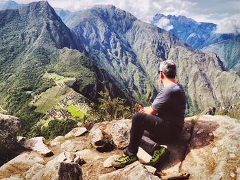 Man sitting on rock looking at mountains