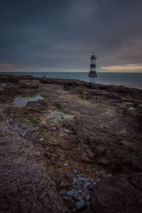 Lighthouse by sea against sky