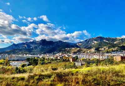 Scenic view of townscape and mountains against blue sky