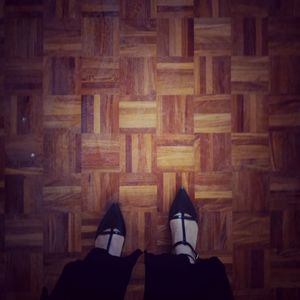 Low section of person wearing shoes on hardwood floor