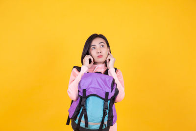 Portrait of a young woman against yellow background