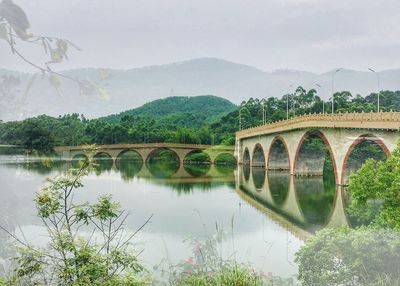 Arch bridge over river against sky