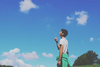 Low angle view of woman standing against blue sky