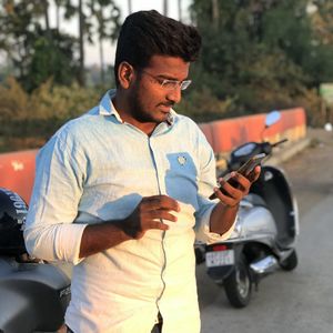 Young man holding camera while standing by car