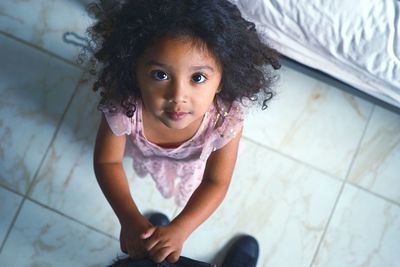 High angle portrait of cute girl standing on tiled floor at home