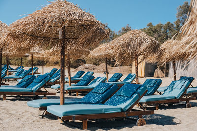 Empty blue sun beds and loungers under the umbrellas on a summer day at a beach in mykonos, greece.