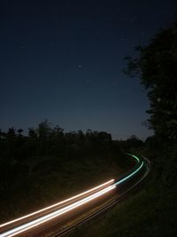 Light trails on road against sky at night