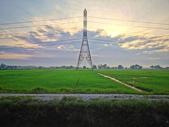 Electricity pylon on field against sky