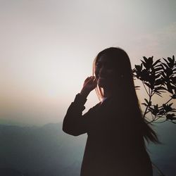 Portrait of silhouette woman standing against sky during sunset