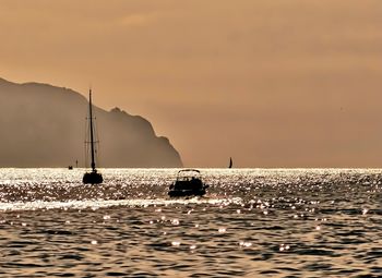 Sailboat sailing on sea against sky during sunset
