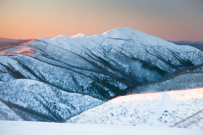 Scenic view of snow covered mountains against sky during sunset