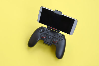 High angle view of camera phone against yellow background