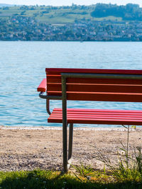 Empty bench on beach by lake