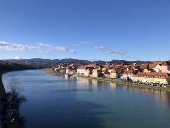 Town by river against sky in city