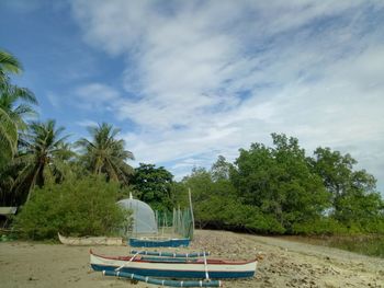 Boat moored on beach against sky