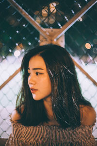 Beautiful woman against chainlink fence at night