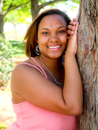 Portrait of young woman sitting on tree