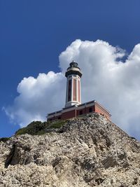 Low angle view of lighthouse by building against sky