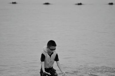 Boy wearing life jacket while playing on shore at beach