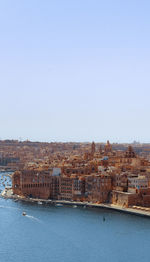 Aerial view of townscape by sea against clear sky